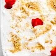 Close up overhead view of dessert topped with sliced strawberries and graham cracker crumbs.