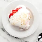 Overhead view of serving of dessert on small white plate by a spoon.