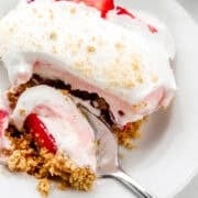 Close up view of serving of dessert on white plate with spoon in it.