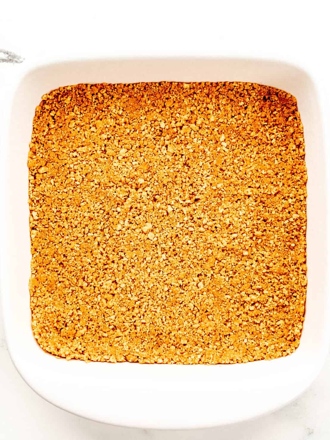 Crust ingredients pressed into the bottom of a square white baking dish. 