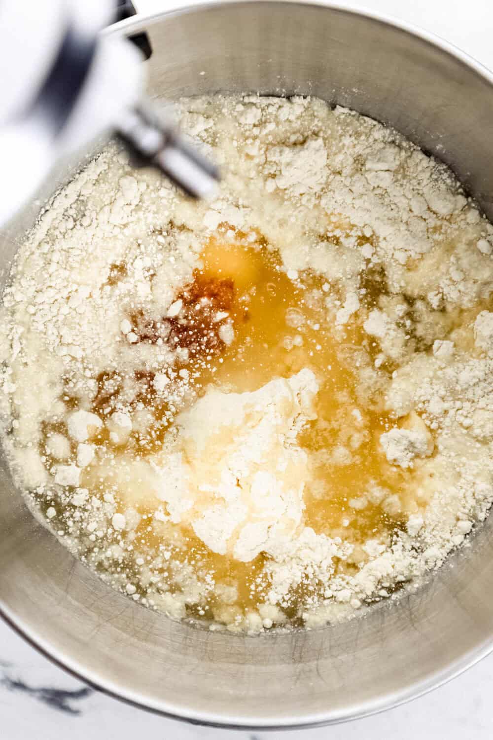 Ingredients to make boxed cake mix added to stand mixer bowl.