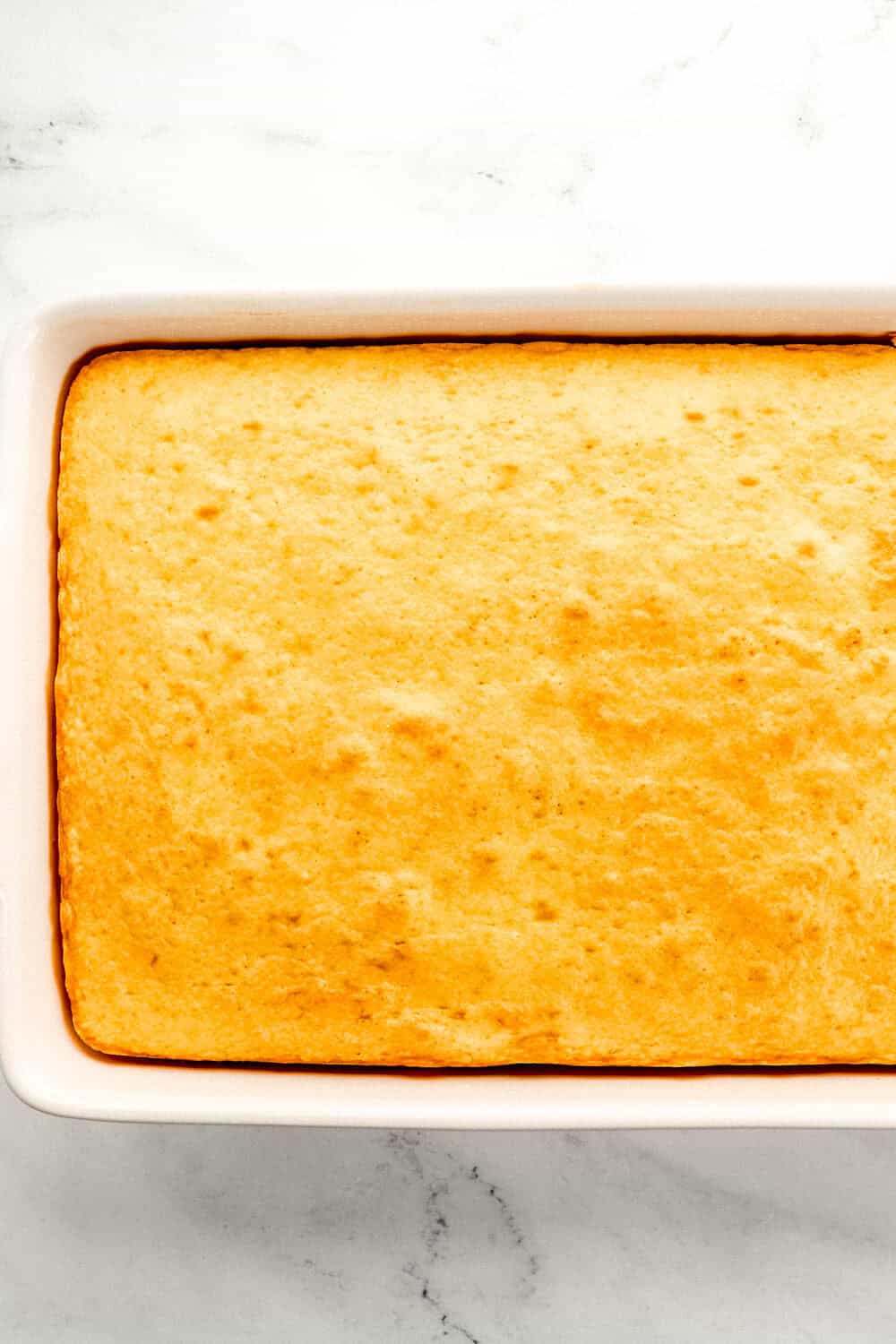 Overhead view of baked cake in white rectangle baking dish.