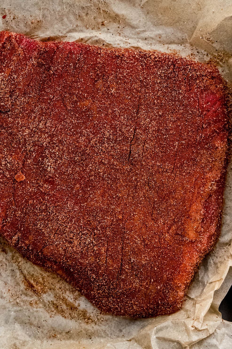 Dry rubbed steak on top of parchment paper.