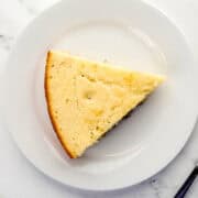 Overhead view of piece of cornbread on white plate by a fork.
