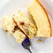 Piece of cornbread on a white plate with a fork in it.