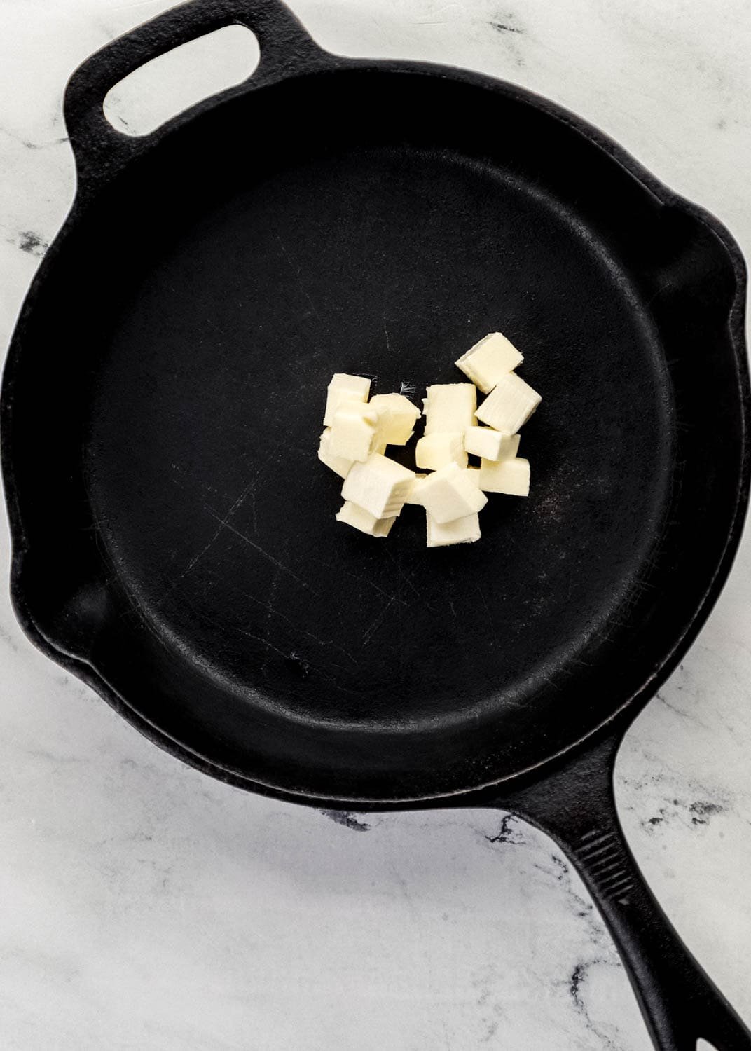 Overhead view of cast iron skillet with butter in it. 