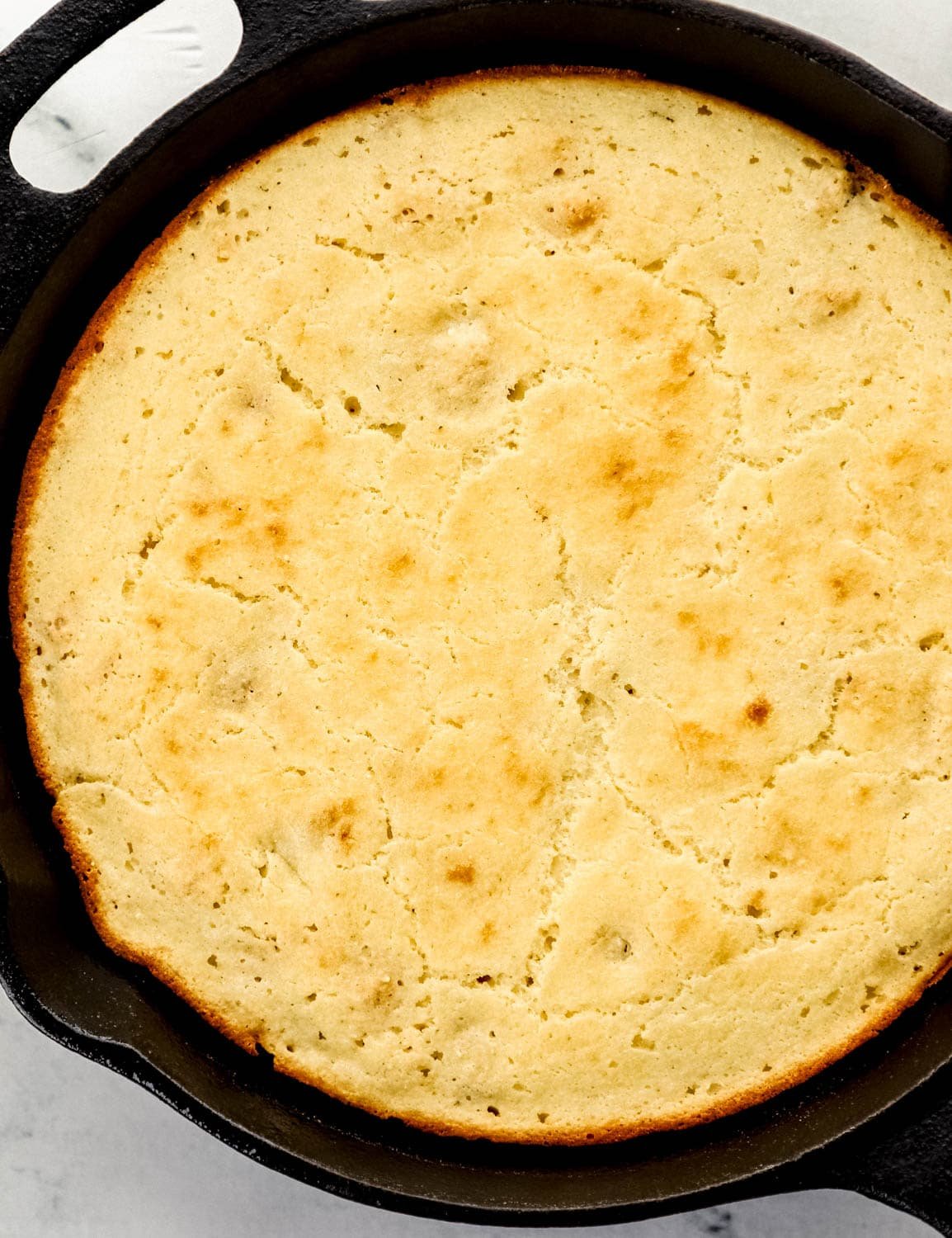 Overhead view of baked cornbread in cast iron skillet. 