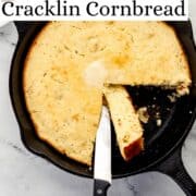 Overhead view of finished cornbread in cast iron skillet with knife in it on pin with text overlay.