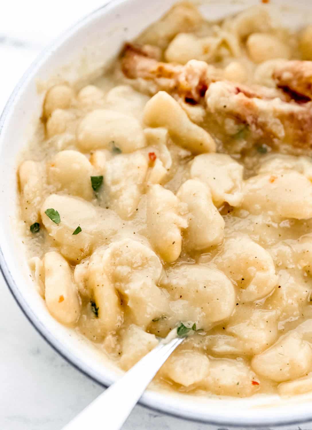 Close up view of beans in white bowl with spoon in it.