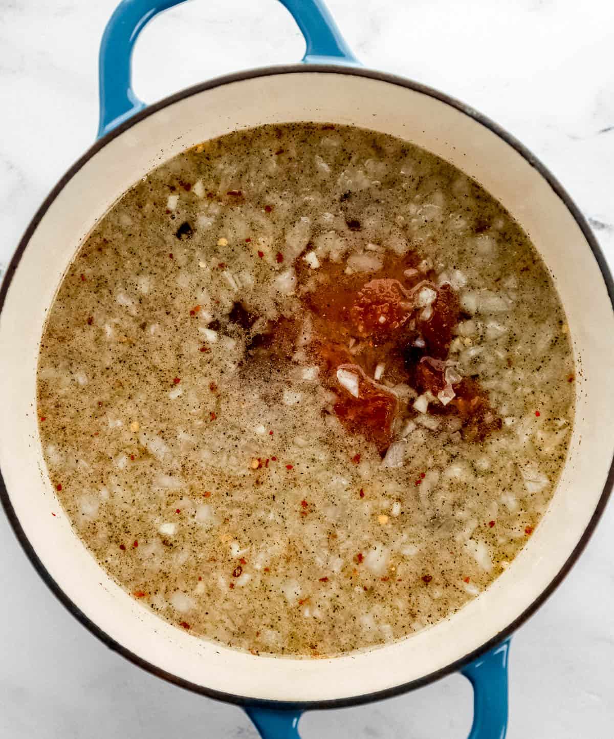 Overhead view of dutch oven with base broth ingredients combined in it.