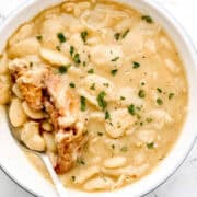 Overhead view of white bowl of beans with spoon in it.