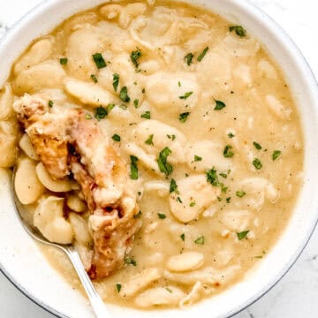 Overhead view of white bowl of beans with spoon in it.