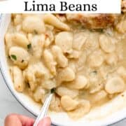 Bowl of beans with spoon in it held by a hand on pin with text overlay.
