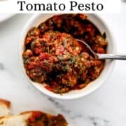 Close up overhead view of pesto in white bowl with spoon in it on pin with text overlay.