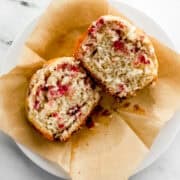 Overhead view of single muffin on top of liner on white plate.