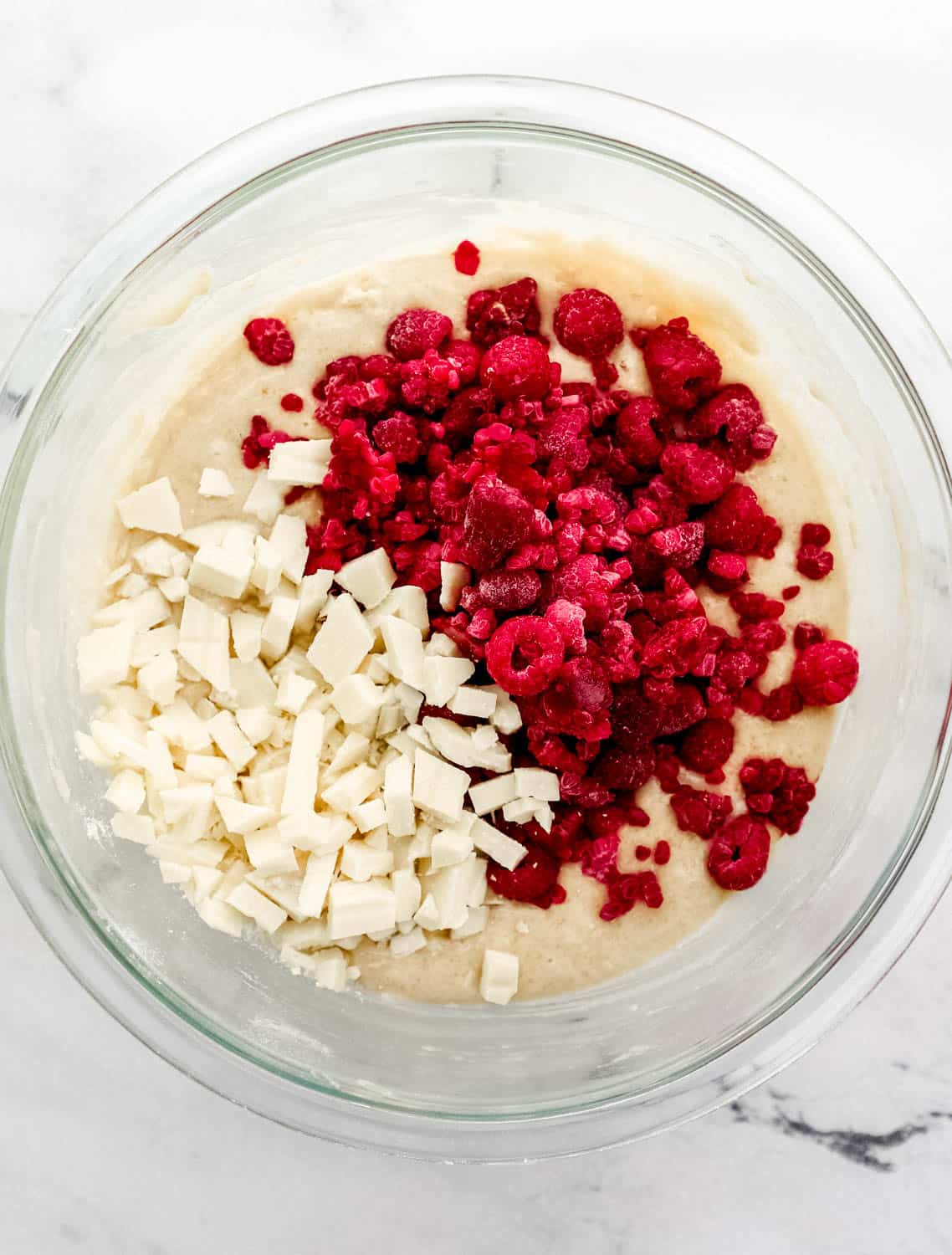 White chocolate and raspberries added to the mixing bowl with the other muffin ingredients.