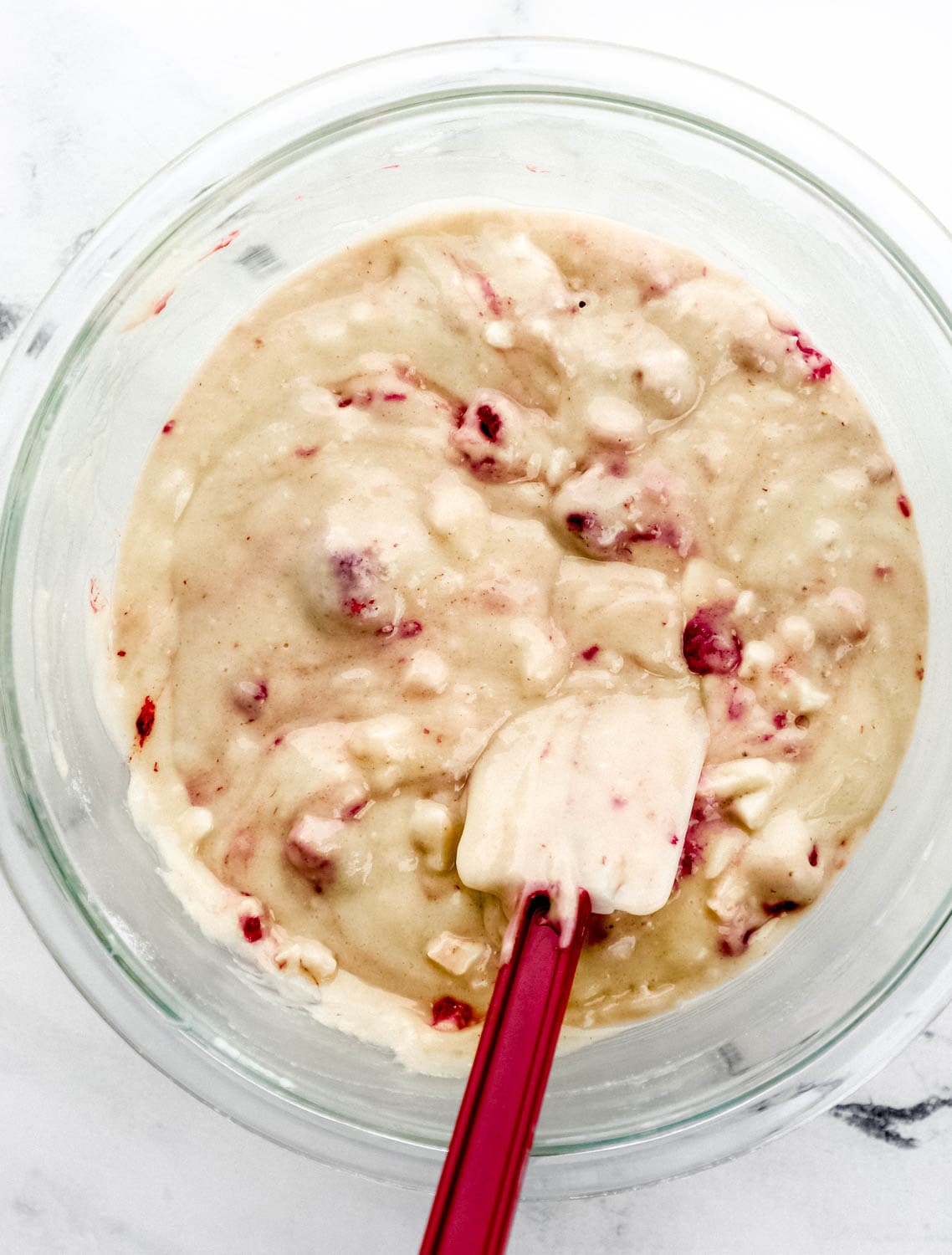 All muffins ingredients combined in glass mixing bowl with rubber spatula.