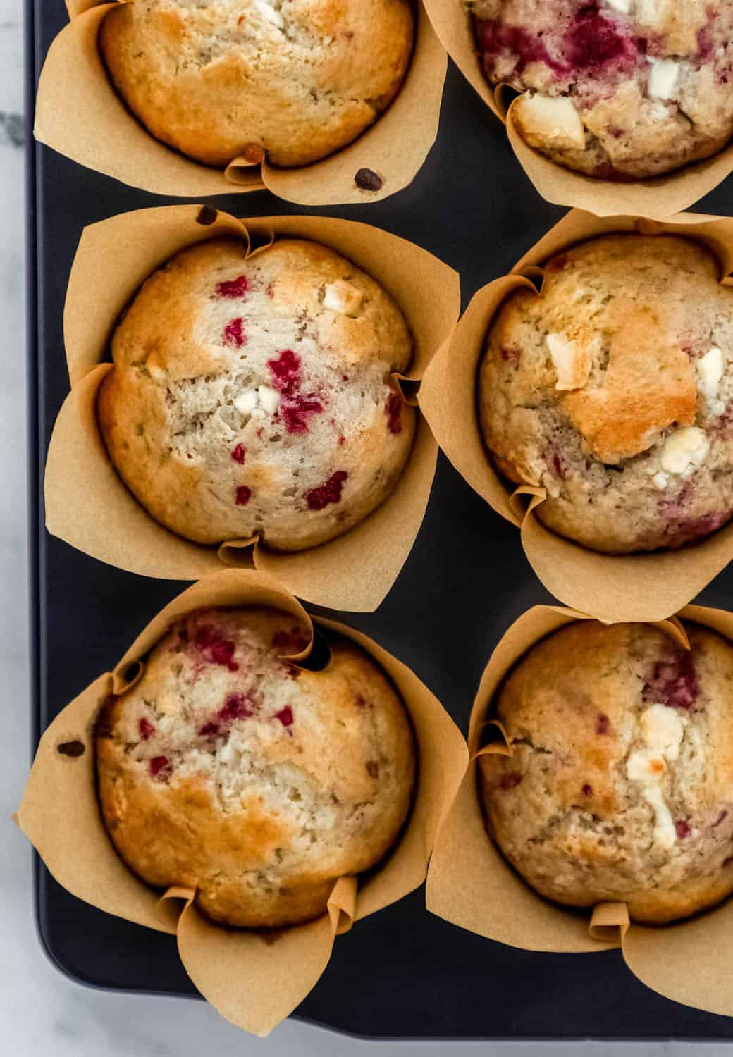 Overhead view of baked muffins in liners in muffin pan.