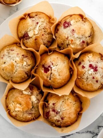 Overhead view of finished muffins on large white plate on marble surface.