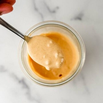 Overhead view of sauce in jar with spoon held over it.
