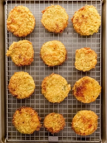 Fried tomatoes on wire rack on top of a sheet pan.
