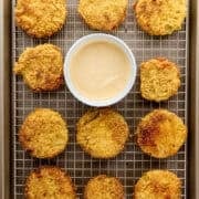 Tomatoes on wire rack sheet pan with small white bowl of sauce.
