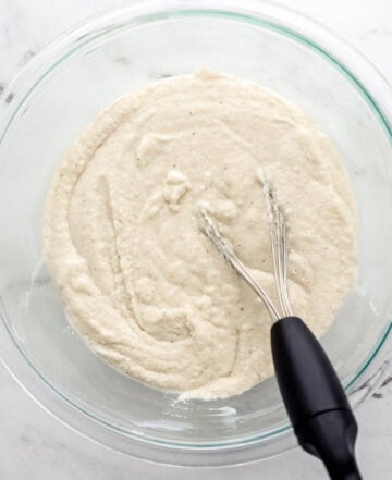 Overhead view of batter in glass mixing bowl with whisk.