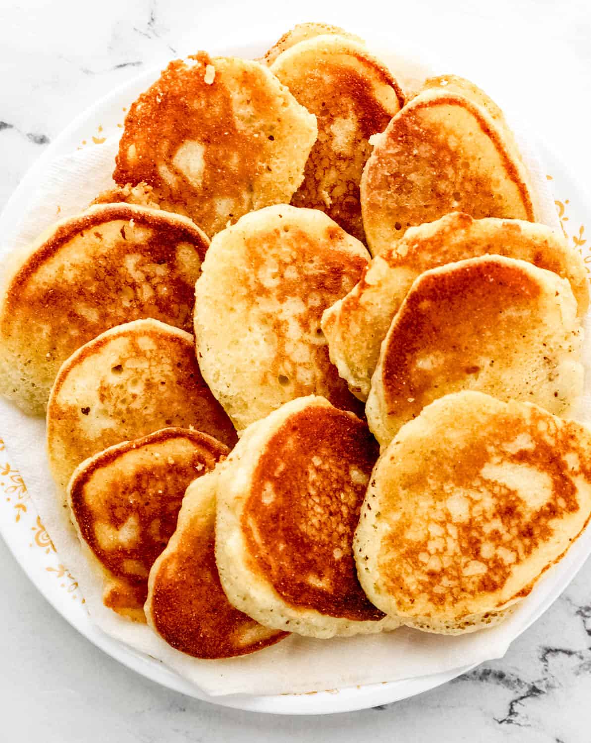 Overhead view of plate of finished hoe cakes on top of marble surface. 