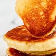 Close up side view of plate of hoe cakes with hand holding one on top on pin with text overlay.