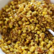 Close up view of corn in a bowl with spoon.