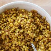 Overhead view of bowl of corn with spoon in it on pin with text overlay.
