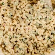 Close up view of salad in a large mixing bowl with wooden spoon.