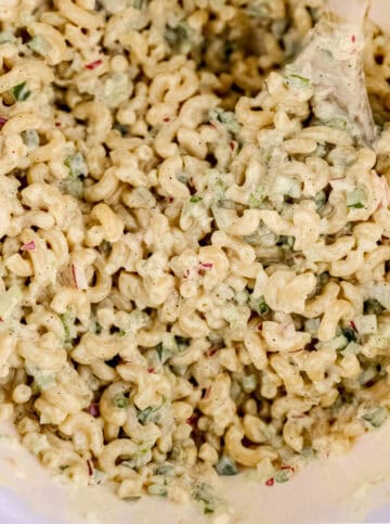 Close up view of salad in a large mixing bowl with wooden spoon.