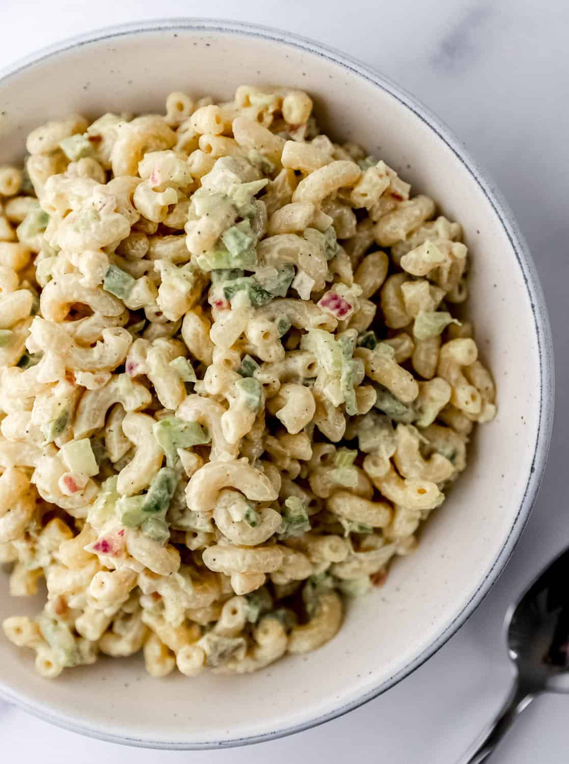 Close up overhead view of bowl of macaroni salad by a spoon. 