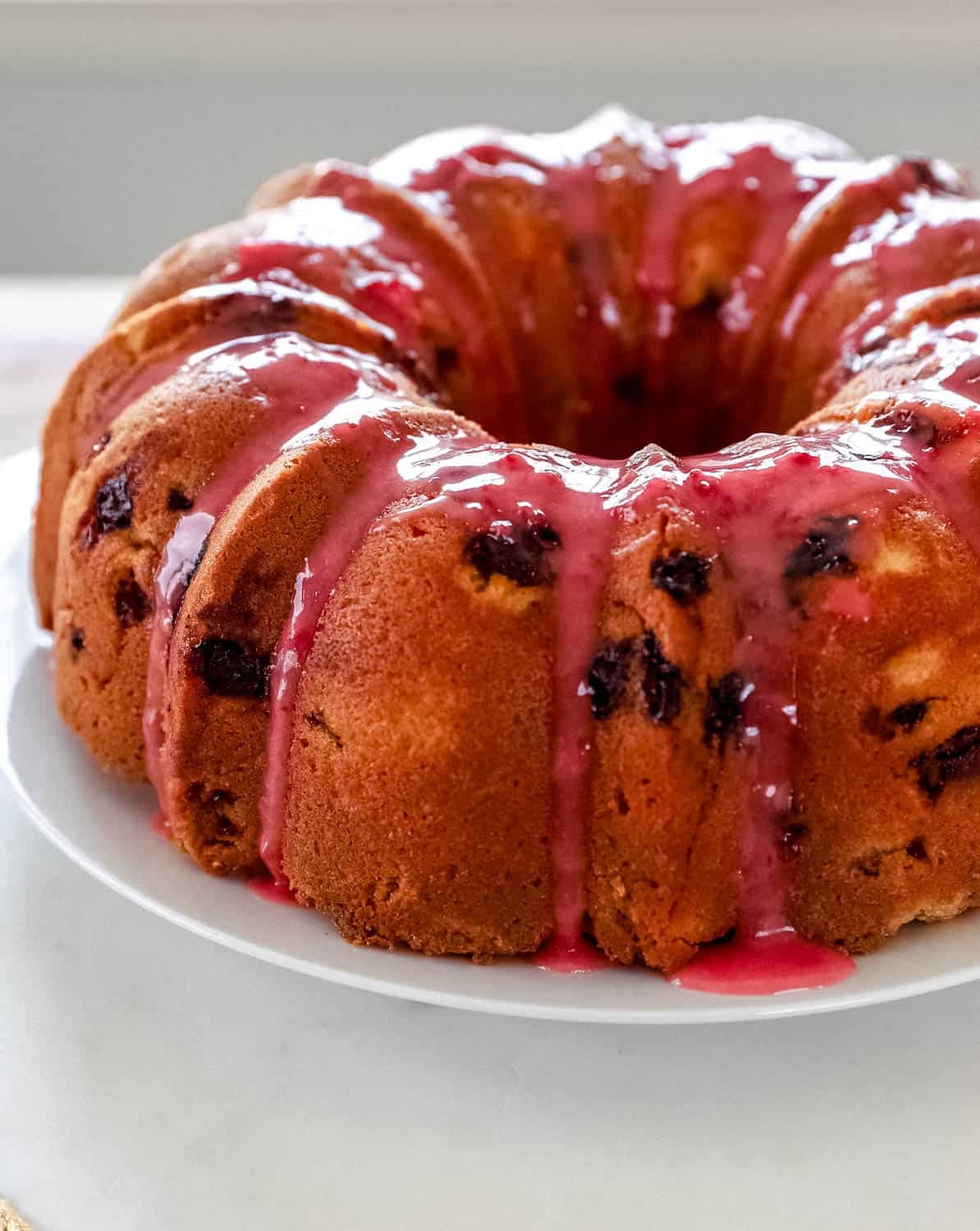 Close up side view of finished cake on white plate topped with glaze. 