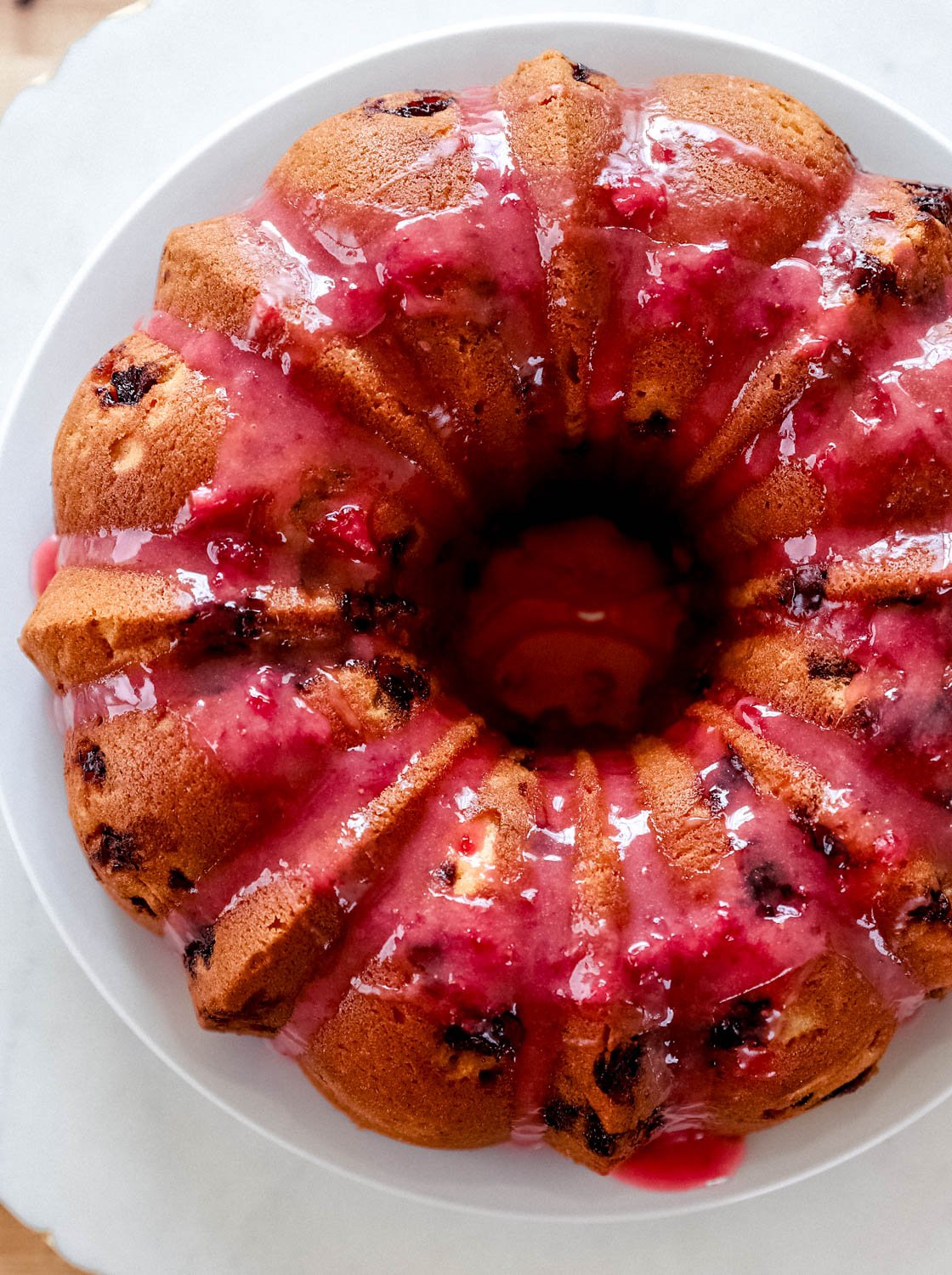 Glazed added to the top of the baked pound cake on white plate. 