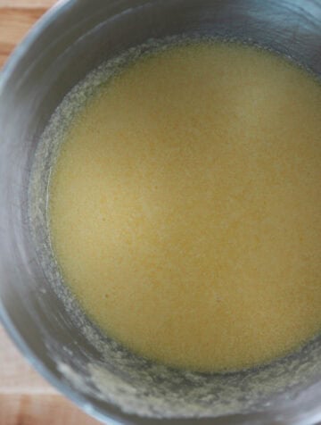 Overhead view of eggs and extracts added to mixing bowl with other ingredients.