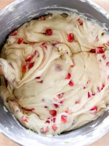 Overhead view of strawberries added to cake batter in mixing bowl.