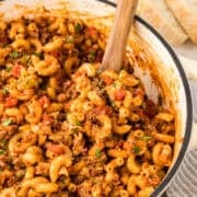Close up front view of pot of goulash with wooden spoon in it.