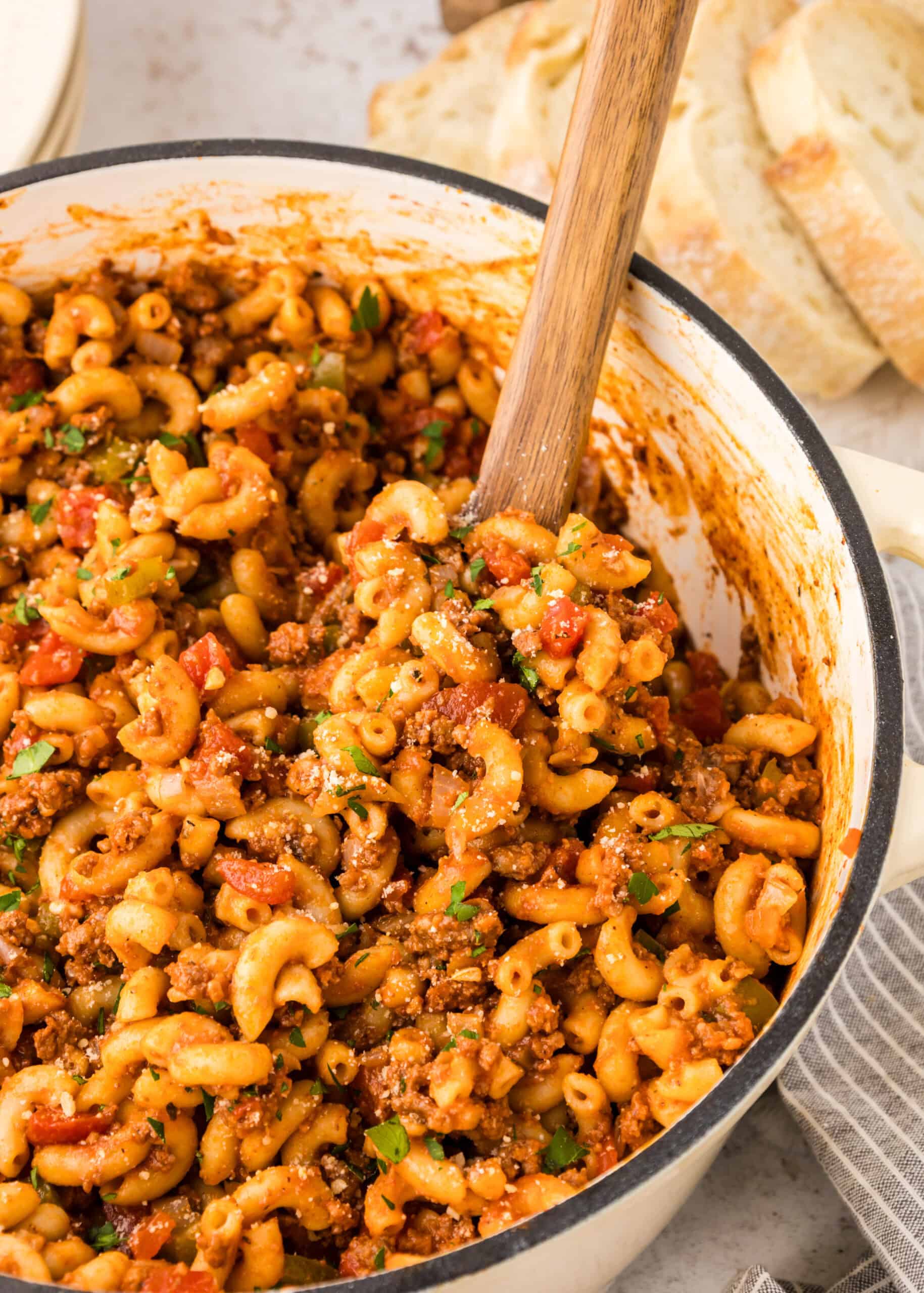 Close up view of goulash in Dutch oven with wooden spoon in it. 