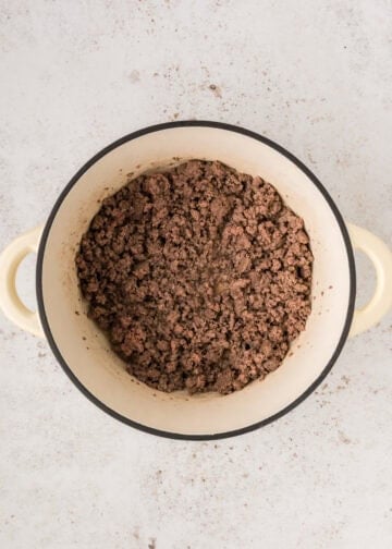 Overhead view of cooked ground beef in white dutch oven.