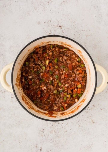 Overhead view of tomato sauce and diced tomatoes added to pot with the other ingredients.