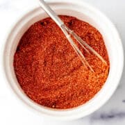 Overhead view of seasoning in a white bowl with whisk.
