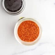 Overhead view of spice blend in small jar by lid.