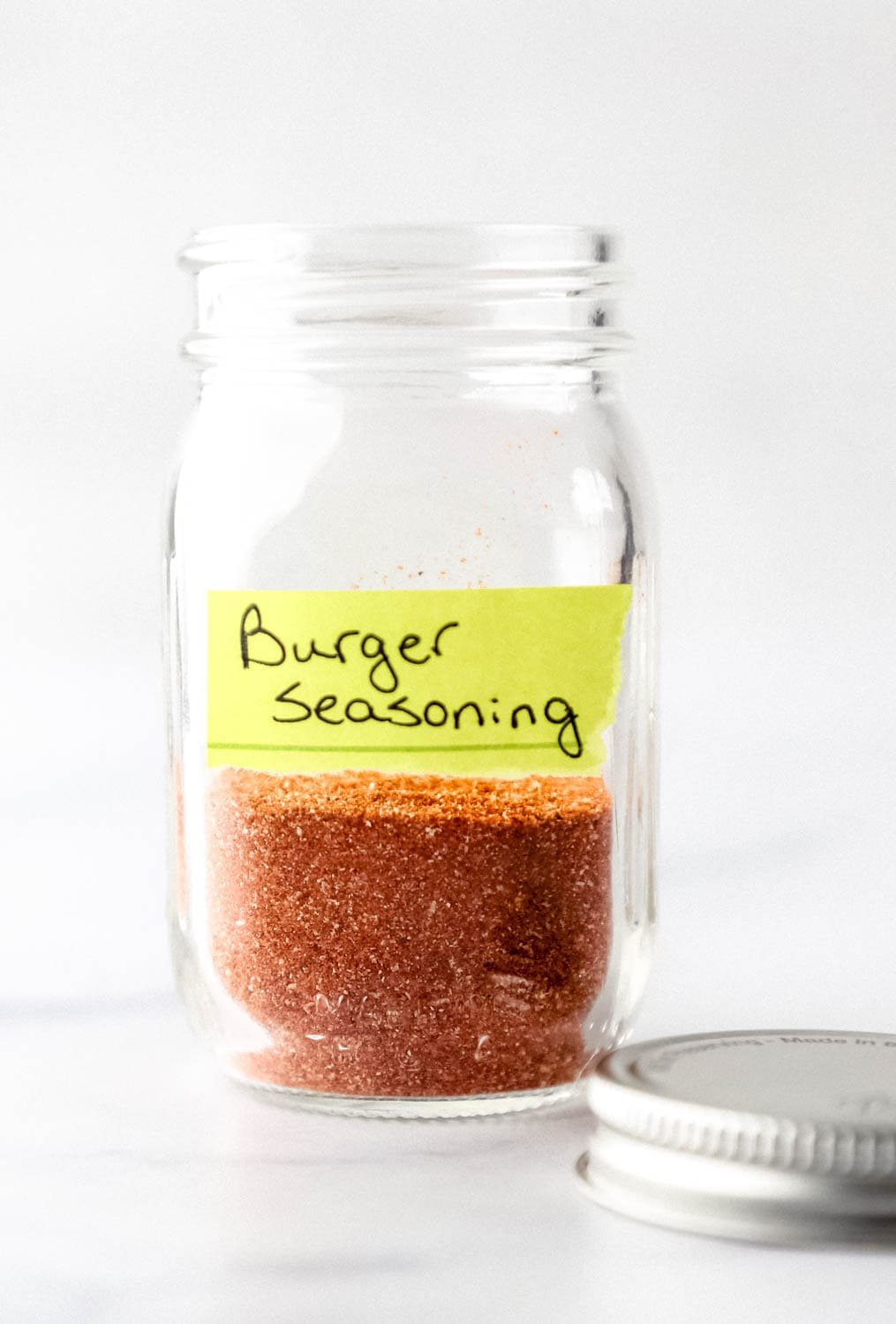 Side view of small jar with label on it and spices in it.