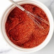 Overhead view of small bowl with seasoning and whisk in it on pin with text overlay.