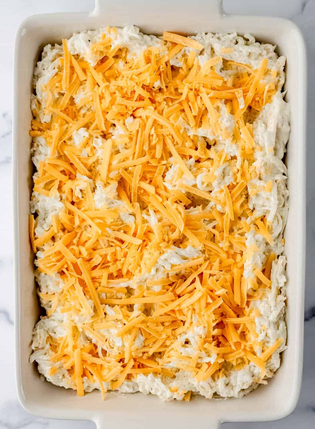 Overhead view of casserole mixture topped with shredded cheese.