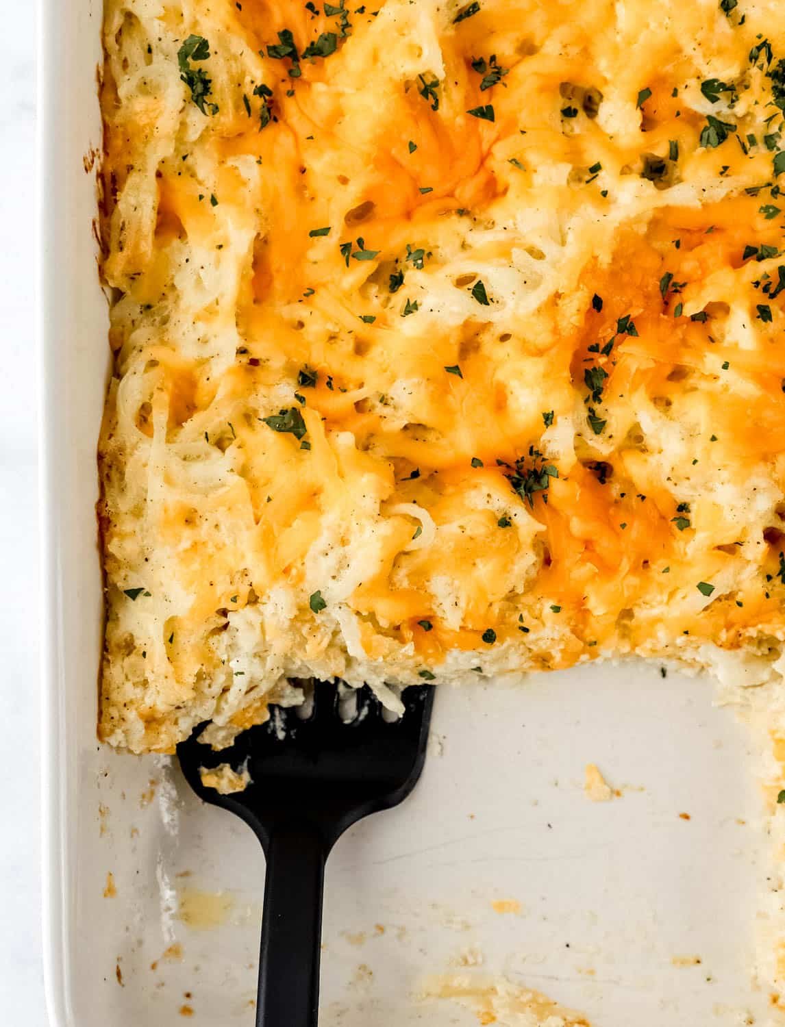 Overhead view of casserole in baking dish with spatula in it.