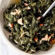 Close up view of bowl of greens with fork in it.