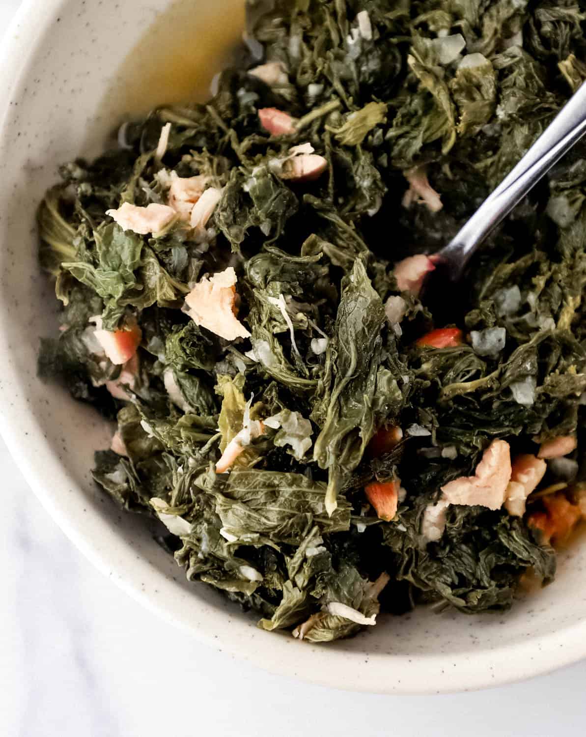 Close up view of finished greens in bowl with fork.